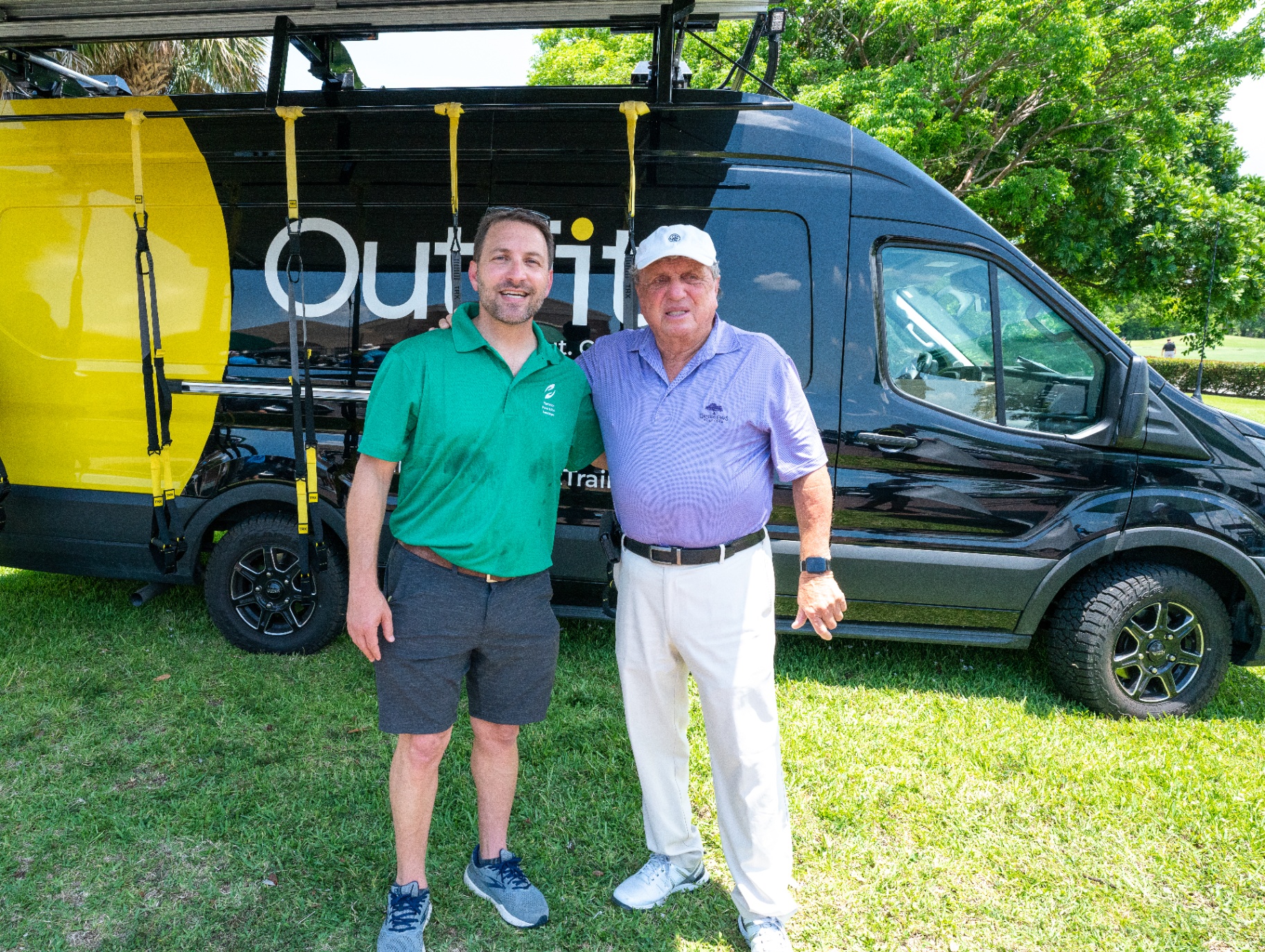 OutFit team member with golf course guest beside the van during a community wellness activation