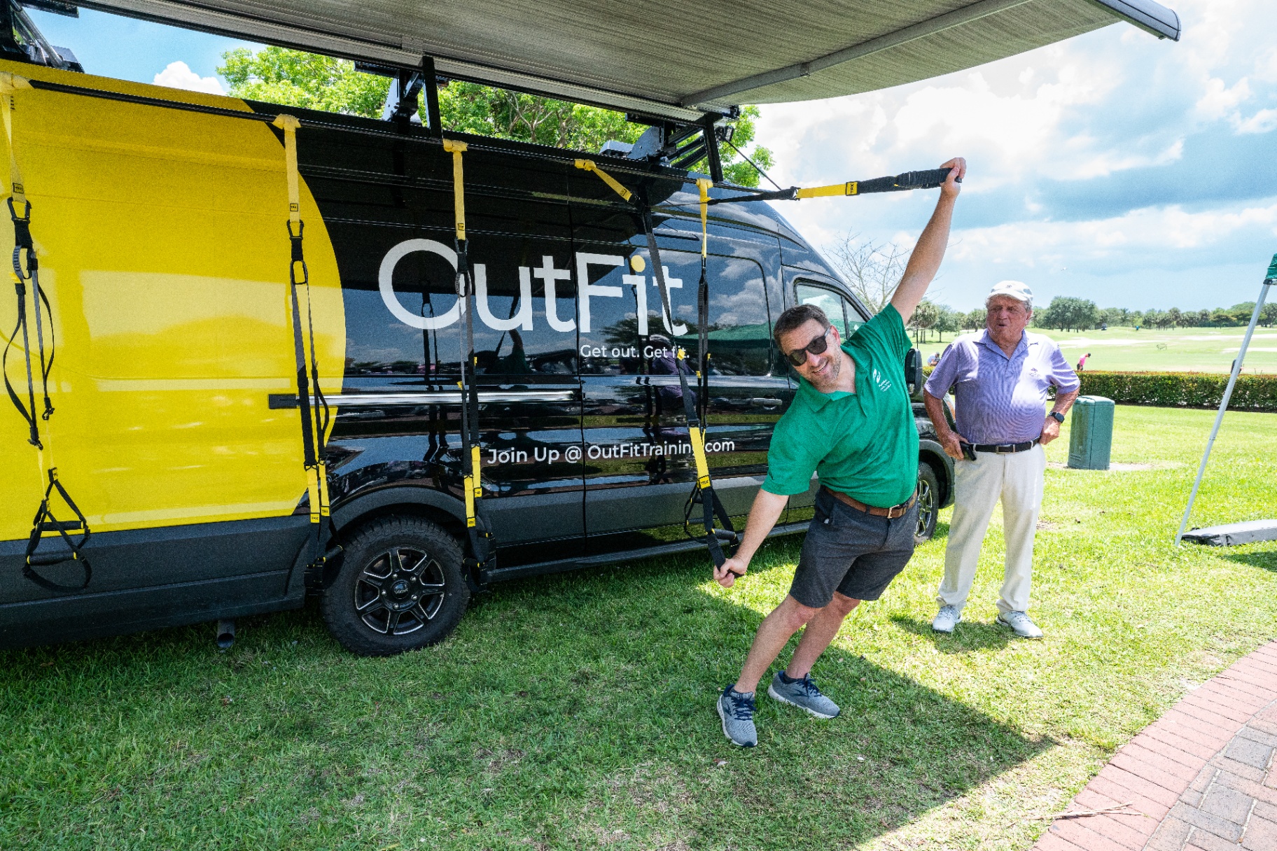 Guest doing TRX movement beside the OutFit van at a golf course event